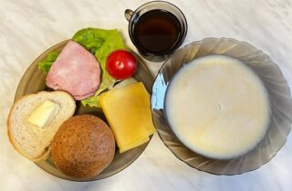 Herbata, zupa mleczna, pieczywo mieszane, masło, szynka Ojca Grzegorza, pomidor, sałata zielona, ser żółty.